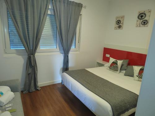 LeisApartamentos en Leis Muxia的一间卧室设有一张床和两个窗户。