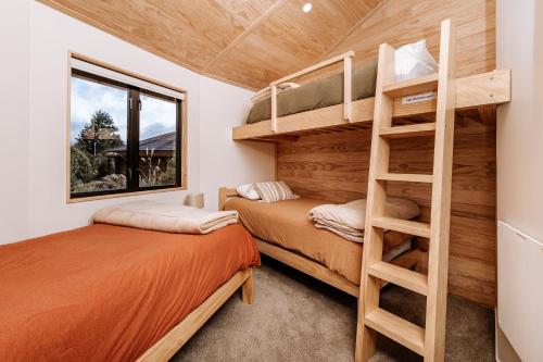 奥阿库尼Kaho - Ohakune Holiday Home with Spa的小型客房设有两张双层床,配有梯子