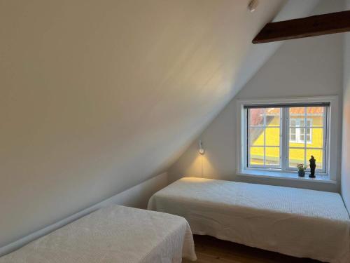 斯瓦讷克Holiday home Svaneke LXII的阁楼卧室设有两张床和窗户。