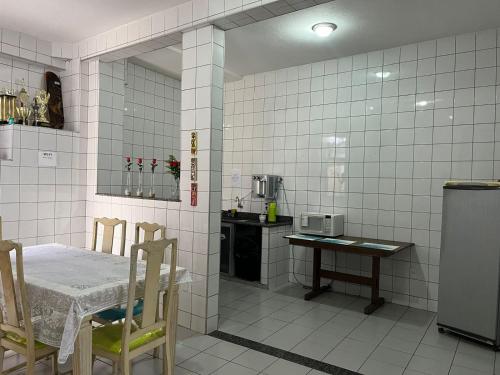 维多利亚Hostel Alto do Rosario的白色瓷砖厨房配有桌子和桌椅