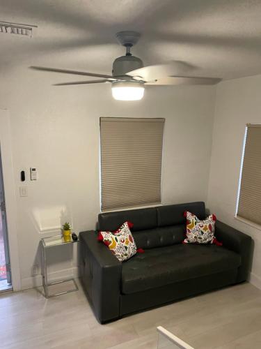 迈阿密Comfortable modern apartment- central location.的客厅配有一张黑色沙发,配有吊扇
