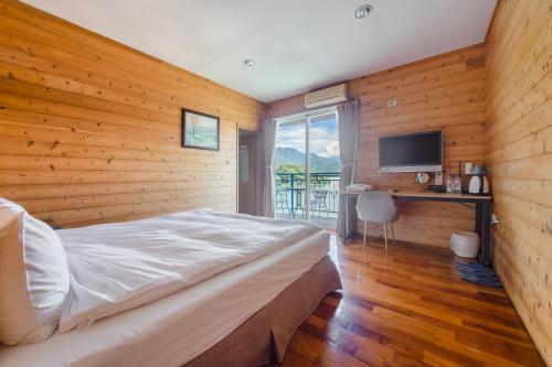 鱼池乡碧水山居湖畔民宿的一间卧室设有木墙、一张床和电视