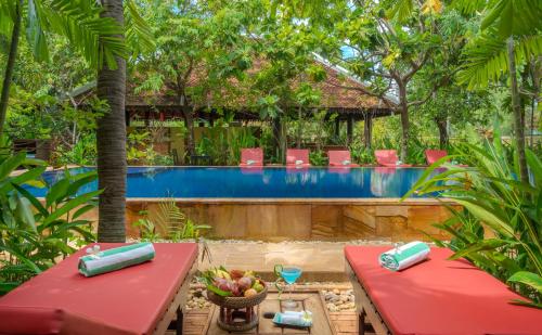 暹粒Pandora Suite D'Angkor的一个带游泳池和红色桌椅的度假酒店