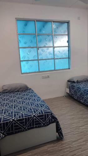 Kampong Baharu CheratingGarlic Cherating Pool Homestay的一间卧室设有两张床和窗户。