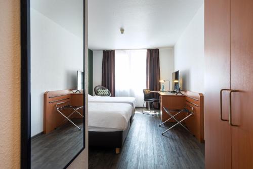 贝格施特拉瑟黑彭海姆ACHAT Hotel Heppenheim的酒店客房带一张床、一张书桌和一面镜子