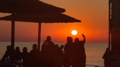 巴尔奇克Family Hotel Morska Zvezda的一群站在海滩上观看日落的人