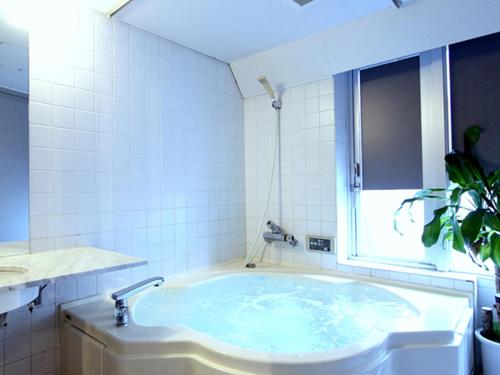 东京HOTEL LiVEMAX BUDGET Korakuen的白色瓷砖浴室内的浴缸