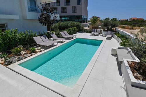 诺瓦利娅VILLA CALA, Hotel Rooms&Apartments的一座带躺椅和椅子的游泳池位于一座建筑旁边
