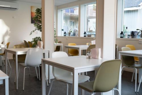 厄斯特松德Hotell Stortorget, Östersund的餐厅设有白色的桌椅和窗户。