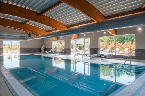 锡河边的圣奥班Golden Tulip Dieppe Hôtel & Spa的蓝色海水和木制天花板的大型游泳池