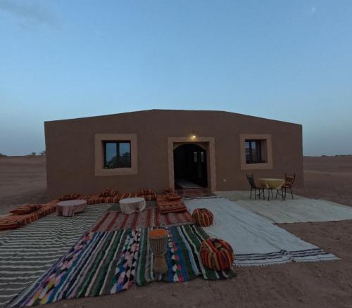 MhamidSahara Luxury Camp M'hamid的沙漠中一座带椅子和地毯的建筑