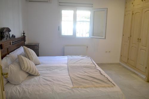诺沃桑克蒂佩特里Chalets en Sancti Petri的一间卧室配有一张带白色床单的床和一扇窗户。