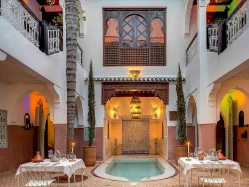 马拉喀什Marrakech Riads, Angsana Heritage Collection的一座带桌子的建筑中间的游泳池