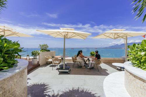 归仁Grand Hyams Hotel - Quy Nhon Beach的两个人坐在桌子下,在伞下