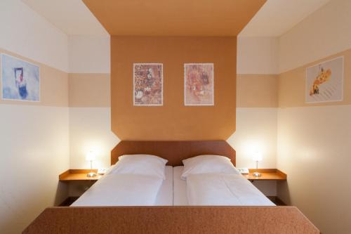 哈尔伯格摩斯古腾堡嘉尼豪斯酒店的一间卧室配有一张带两个枕头和两个灯的床。