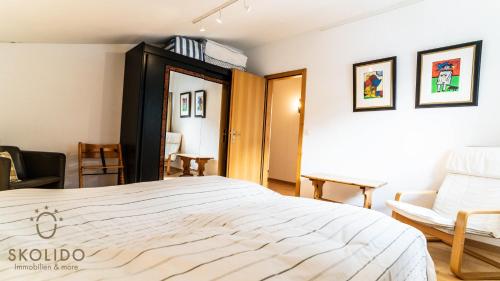 布赖滕Haus Cotton 4.5 Room Apartment的卧室配有一张白色大床和一把椅子