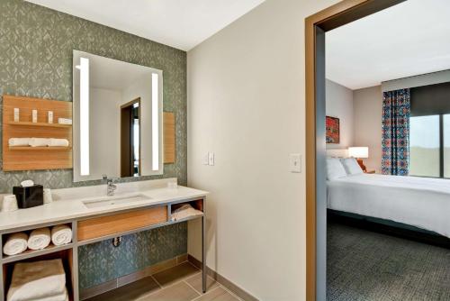 比洛克西Hilton Garden Inn Biloxi的一间带水槽、床和镜子的浴室