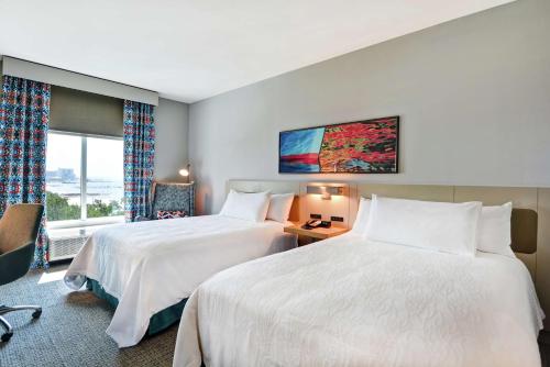 比洛克西Hilton Garden Inn Biloxi的酒店客房设有两张床和窗户。