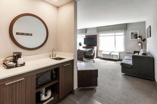 魁北克市Hampton Inn & Suites by Hilton Québec - Beauport的一间带水槽和镜子的浴室和一间客厅
