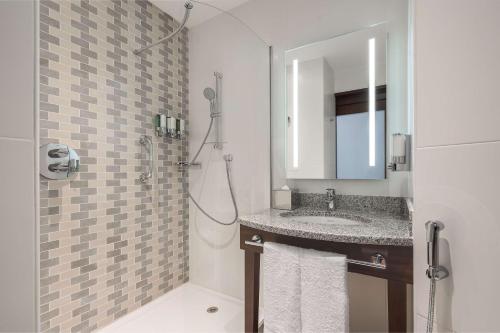 迪拜Hampton By Hilton Dubai Al Barsha的浴室配有盥洗盆和带镜子的淋浴