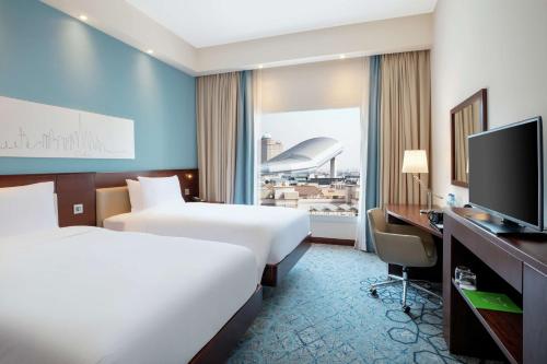迪拜Hampton By Hilton Dubai Al Barsha的酒店客房设有两张床和一台平面电视。