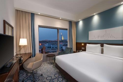 迪拜Hampton By Hilton Dubai Al Barsha的配有一张床、一张书桌和一扇窗户的酒店客房