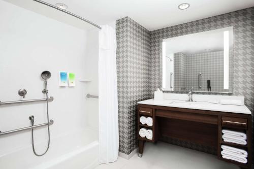 YaphankHome2 Suites by Hilton Long Island Brookhaven的一间带水槽、浴缸和镜子的浴室