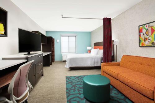 YaphankHome2 Suites by Hilton Long Island Brookhaven的酒店客房设有一张沙发和一张床