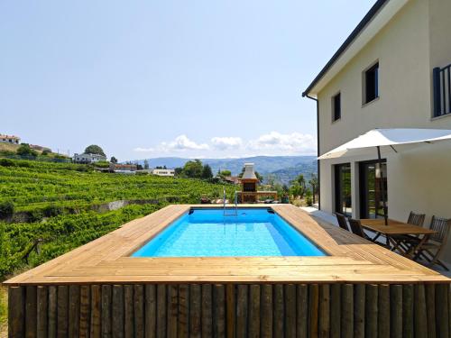 Santa Cruz do DouroCasa da Milinha - Villa with a Pool near Rio Douro的一座带木甲板的游泳池,位于一座房子旁边