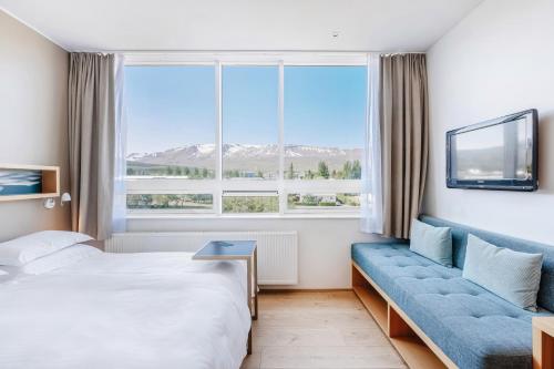 阿克雷里Akureyri - Berjaya Iceland Hotels的酒店客房设有床、沙发和窗户。