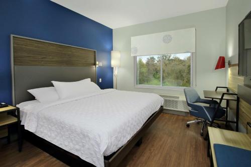 莫比尔Tru By Hilton Mobile的卧室配有床、椅子和窗户。