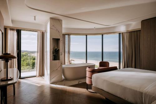 斯维诺乌伊希切Hilton Swinoujscie Resort And Spa的酒店客房配有一张床和一个浴缸,享有海景。