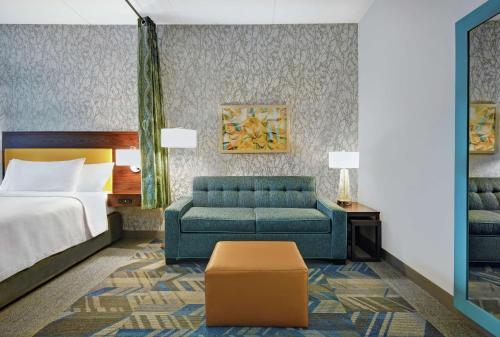 罗维莎Home2 Suites By Hilton Lawrenceville Atlanta Sugarloaf, Ga的酒店客房,配有床和蓝色的沙发