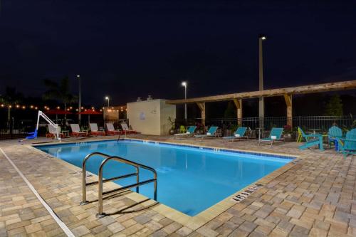 萨拉索塔Home2 Suites by Hilton, Sarasota I-75 Bee Ridge, Fl的夜间游泳池,配有桌椅