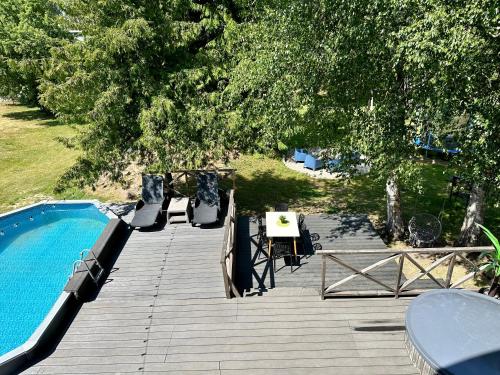 VecumniekiSemo guest house with amazing sauna and pool的木甲板,毗邻游泳池和树木