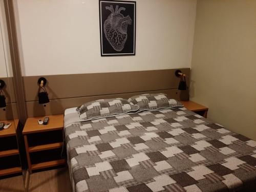 桑托斯Atlantico Flat Gonzaga的一间卧室配有一张带 ⁇ 子毯子的床和两张桌子