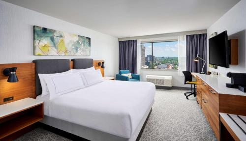 温莎DoubleTree by Hilton Windsor, ON的酒店客房设有一张白色大床和一张书桌