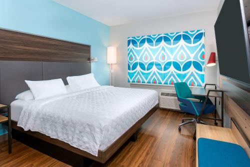 斯帕坦堡Tru By Hilton Spartanburg的酒店客房,配有一张床和一张蓝色椅子