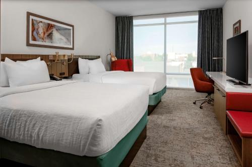 钱德勒Hilton Garden Inn Chandler Downtown的酒店客房设有两张床和一台平面电视。