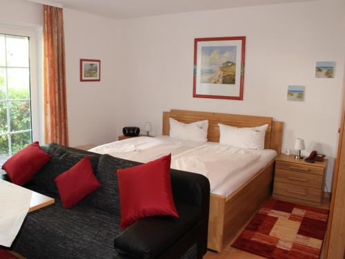 奥茨塞巴德·迪尔哈根Ferienwohnung Mone的一间卧室配有一张床和一张带红色枕头的沙发