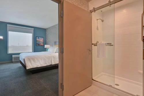科珀斯克里斯蒂Home2 Suites Corpus Christi Southeast, Tx的一间卧室设有一张床和一个玻璃淋浴间