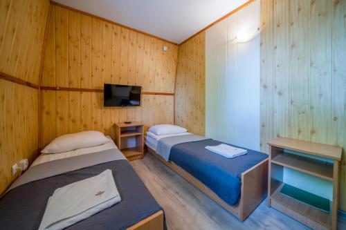 米兹多洛杰OW格罗玛达博德布卡米酒店的配有木墙和电视的客房内的两张床