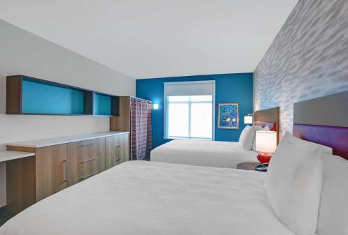 墨尔本Home2 Suites By Hilton Melbourne Viera的一间卧室设有两张床,拥有蓝色的墙壁。