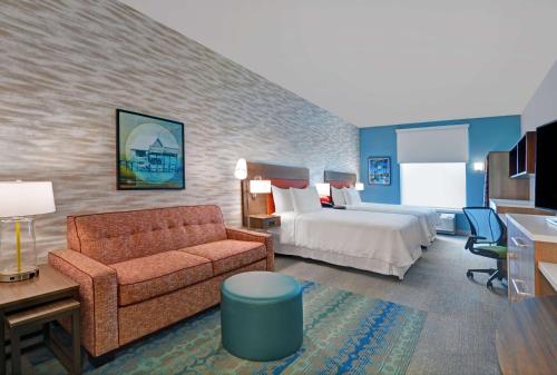 迈尔斯堡Home2 Suites by Hilton Fort Myers Colonial Blvd的酒店客房,配有床和沙发