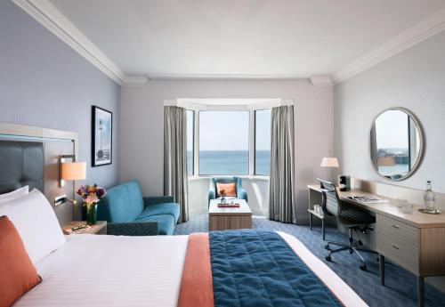 布莱顿霍夫Leonardo Royal Hotel Brighton Waterfront的酒店客房设有一张大床、一张书桌和一张书桌。