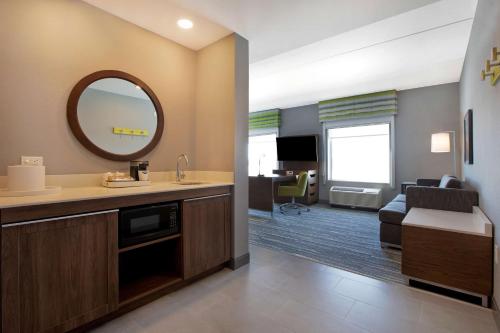 渥太华Hampton Inn & Suites Ottawa West, Ontario, Canada的一间带水槽和镜子的浴室和一间客厅