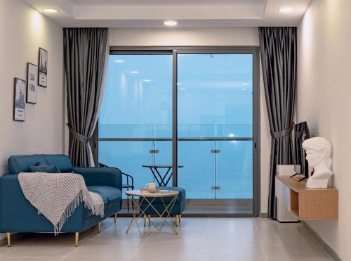 胡志明市Louisa The Gold View Apartment的客厅设有蓝色的沙发和大窗户