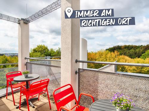 斯图加特ACHAT Hotel Stuttgart Airport Messe的阳台的天井配有红色椅子和桌子