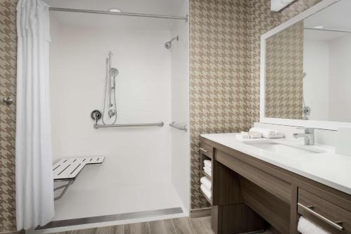 坦帕Home2 Suites By Hilton Tampa Westshore Airport, Fl的带淋浴、盥洗盆和镜子的浴室