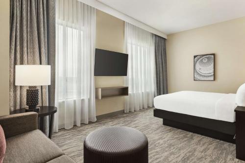 圆石城Embassy Suites by Hilton Round Rock的配有一张床和一把椅子的酒店客房